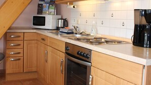 A kitchen with wooden cabinets, a microwave, a coffee maker, and a stove.