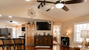 A spacious living room with a brown leather sofa, a wooden coffee table, and a ceiling fan.