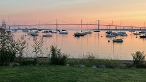 Ein Yachthafen mit vertäuten Booten, im Hintergrund eine Brücke und im Vordergrund Grünflächen.