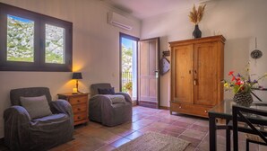 A living room with two armchairs, a wooden cabinet, a glass table, and a view through a window. - Boutique B&B Casa La Calera 15+/ Caminito del Rey-15 min/Ronda-25 min/Town-5 min (Teba)