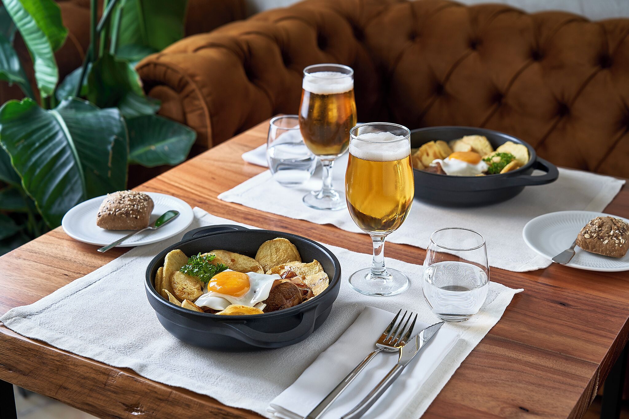 Une table à manger avec un bol de nourriture, un verre de bière et une assiette contenant une pâtisserie.