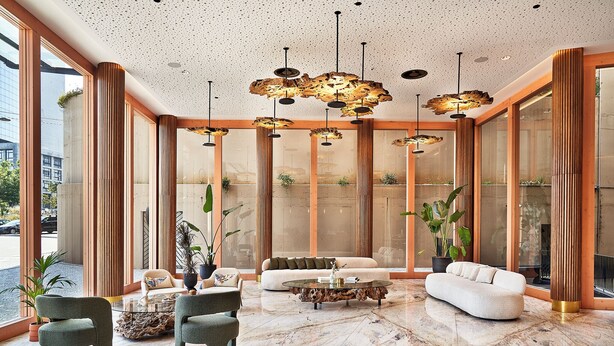 Eine großzügige Lobby mit modernem Design, inklusive einer geräumigen Sitzecke mit Sofas und Sesseln, einem Marmorboden und einer außergewöhnlichen Deckenleuchte.