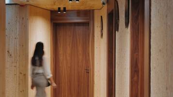 A wooden hallway with a green patterned carpet, wooden walls, and a door at the end.