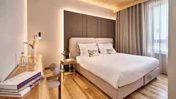 Habitación de hotel moderna con una cama grande, un escritorio con libros, una lámpara y una mesita de noche.