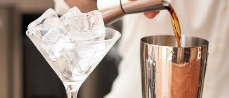 Un barista che versa un drink in un bicchiere da martini.