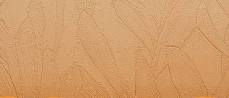 A tufted orange sofa with a textured beige wall in the background.