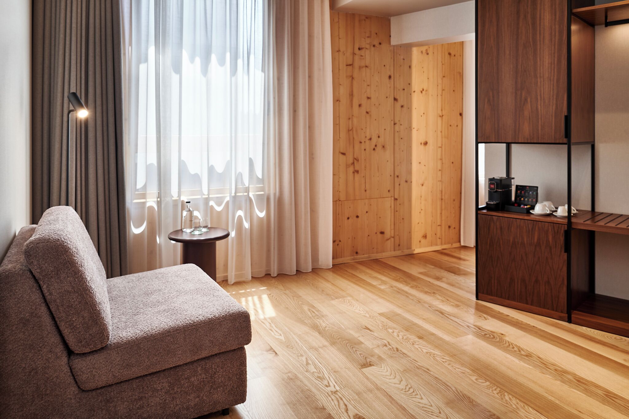Una sala moderna con sofá, cafetera y una pared de madera.