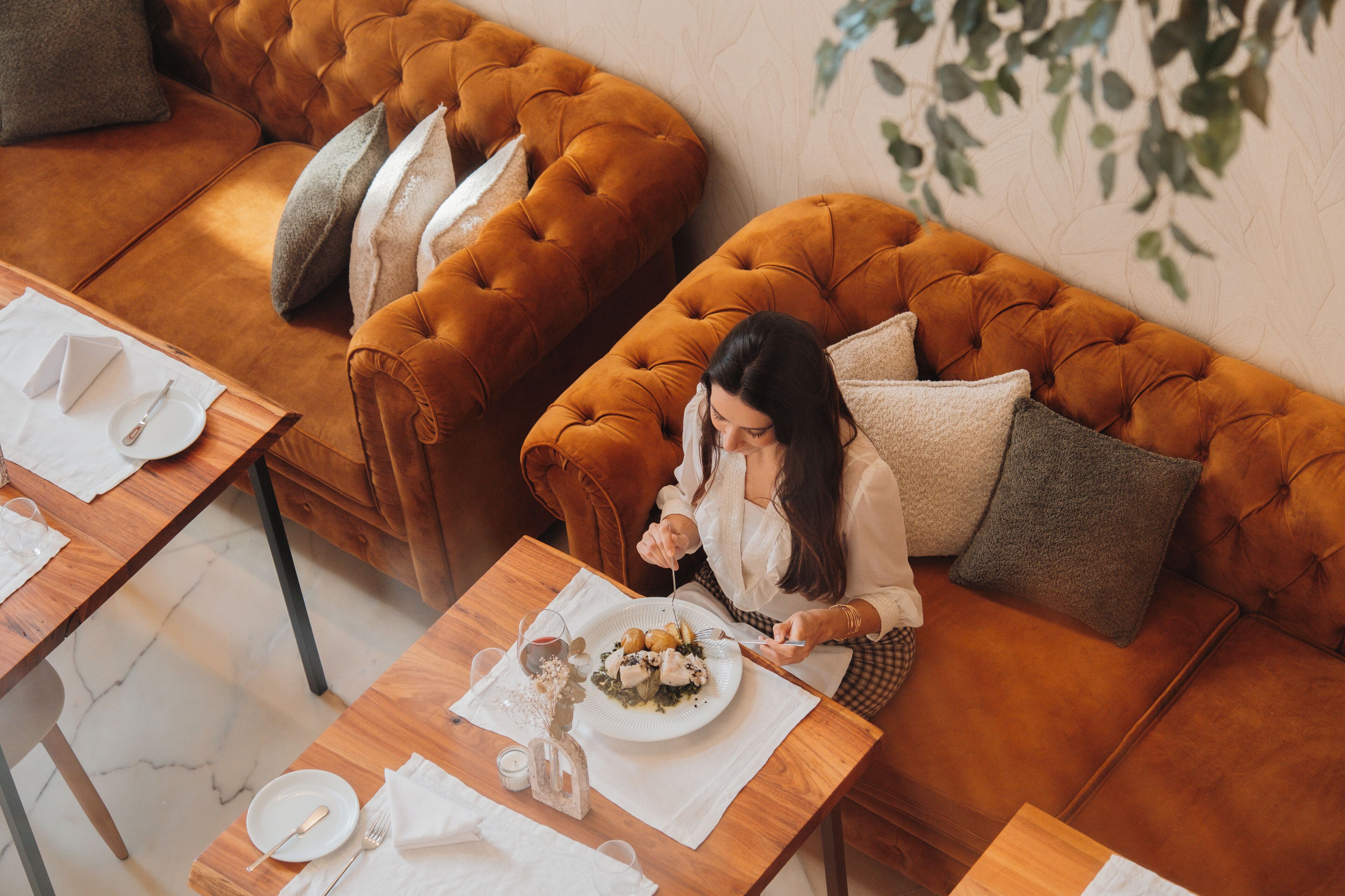 A cozy dining area with a tufted sofa and a wooden table set for a meal.