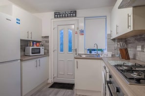 Une cuisine de taille réduite équipée d’un four à micro-ondes, d’une cuisinière et de placards.