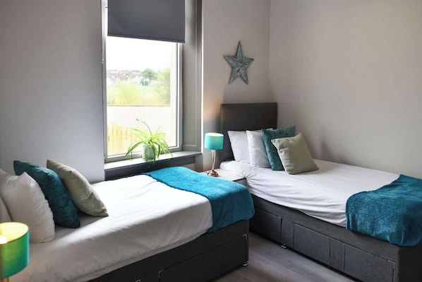Une chambre avec deux lits, une dĂ©coration en forme dâĂ©toile sur le mur, une fenĂȘtre avec vue et une lampe de chevet.