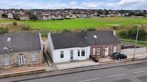 Un quartier résidentiel avec des maisons, une route et un champ verdoyant.