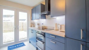 A modern kitchen with dark cabinets, a built-in oven, and a large window.