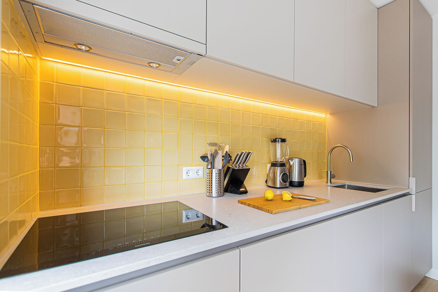 A modern kitchen with a built-in stove, a sink, and a coffee maker.