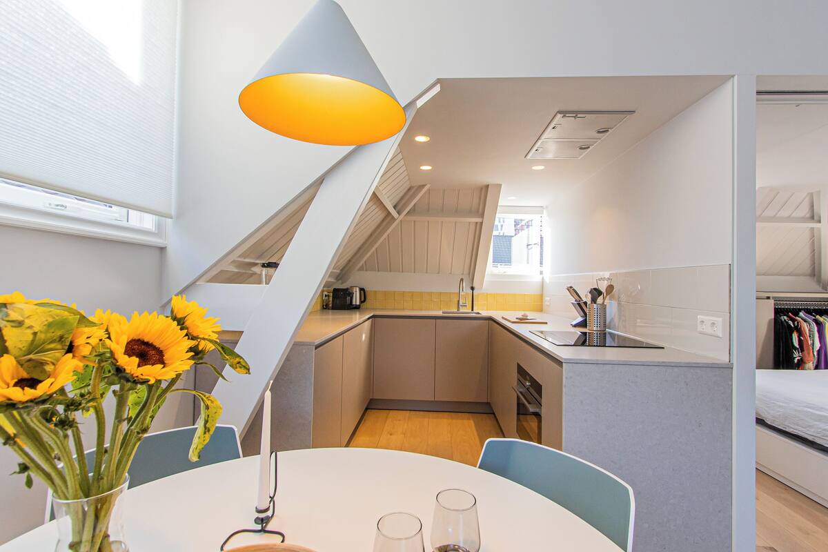 A compact kitchen with a sink, stove, and a small dining area with a table and chairs.