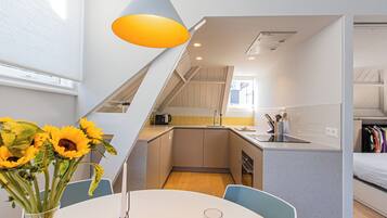 A compact kitchen with a sink, stove, and a small dining area with a table and chairs.