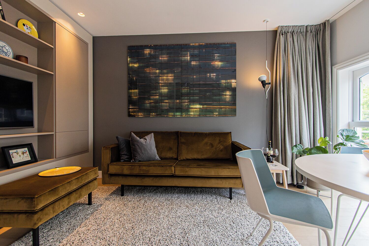 Een moderne woonkamer met een bank, een salontafel, een televisie en een eethoek.
