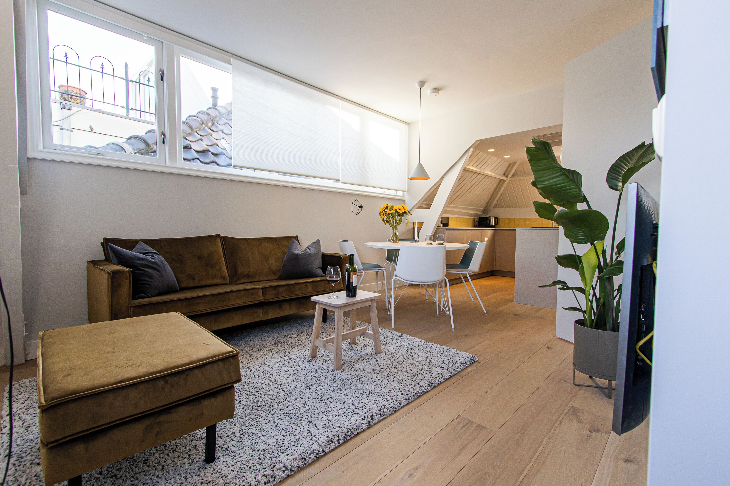 Una sala de estar moderna con un sofá, un reposapiés y una mesita con un jarrón de flores.