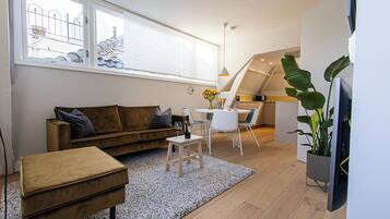 Una sala de estar moderna con un sofá, un reposapiés y una mesita con un jarrón de flores.