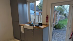 A compact kitchen with a sink, countertop, and a window overlooking a garden.