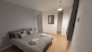 A bedroom with a bed, a nightstand, a mirror, and a ceiling light.
