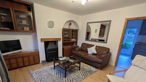 A living room with a fireplace, sofa, coffee table, and a television.
