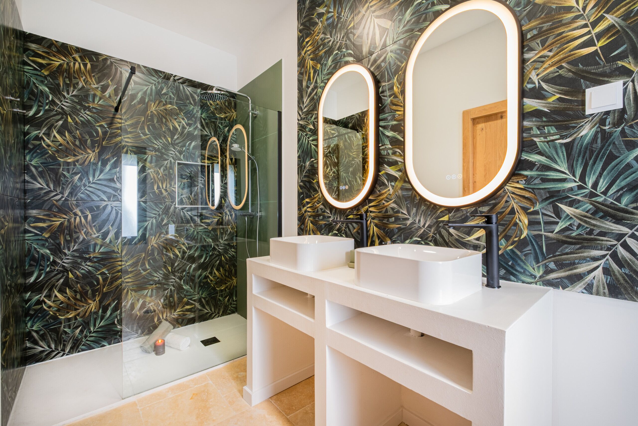 A modern bathroom with two white sinks, a large mirror with illuminated edges, and a shower area.
