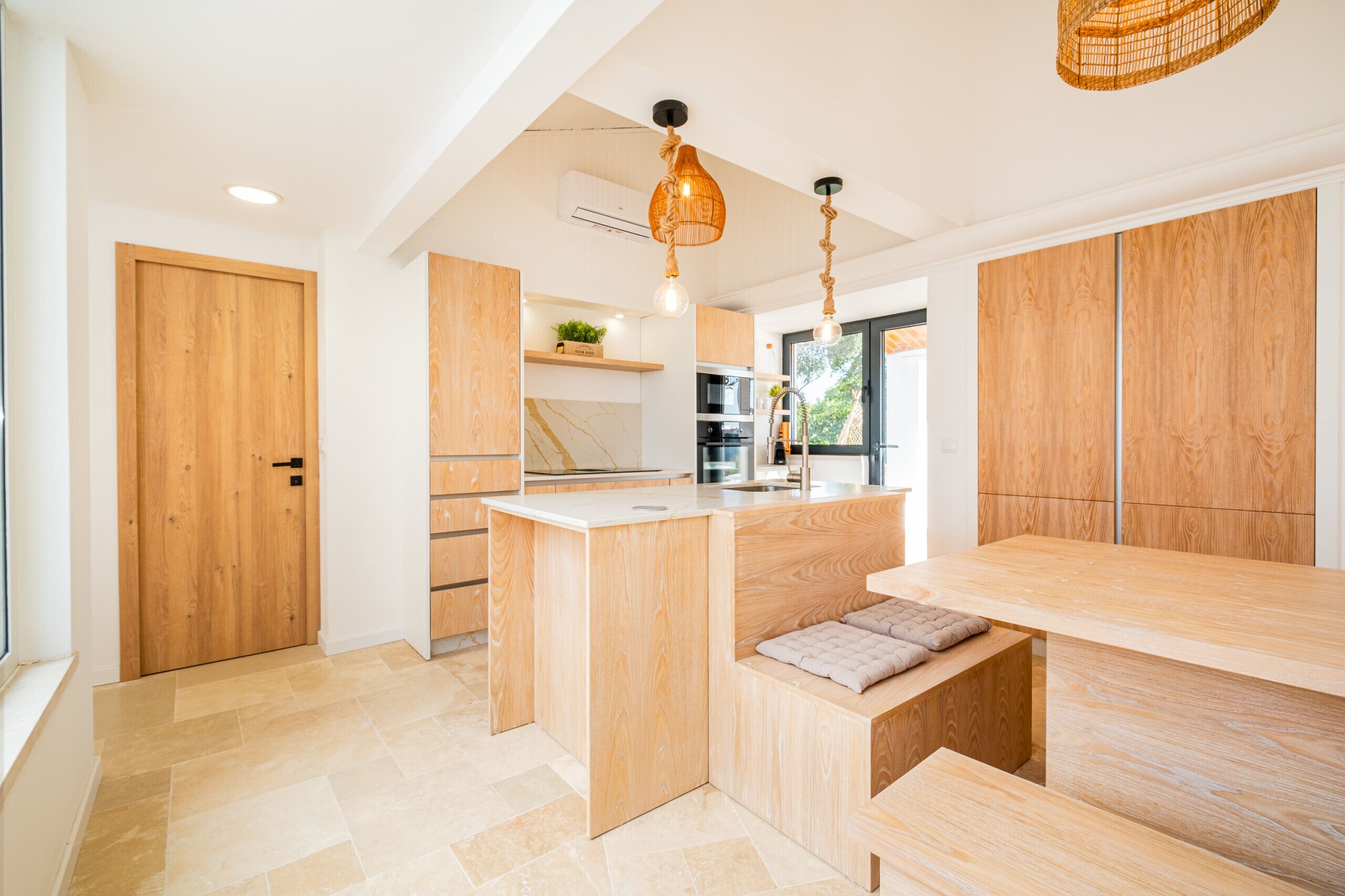 Una cocina moderna con armarios de madera, una isla central e iluminación colgante.
