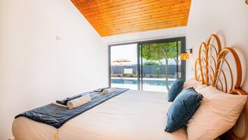 A bedroom with a large bed, wooden ceiling, and a view of an outdoor swimming pool.