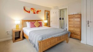 Une chambre à coucher avec un lit en bois, des lampes de chevet, une commode et une porte.