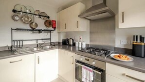 Une cuisine moderne équipée d’appareils électroménagers en acier inoxydable, d’une cuisinière à gaz et d’un égouttoir à vaisselle.