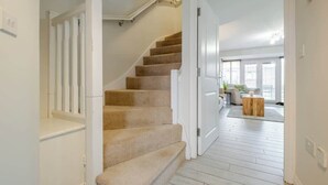 Un escalier menant à un espace situé au deuxième étage, doté d’un plancher de couleur claire et de murs blancs.