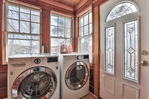 Laundry room with two washing machines and a view of the outdoors through large windows.