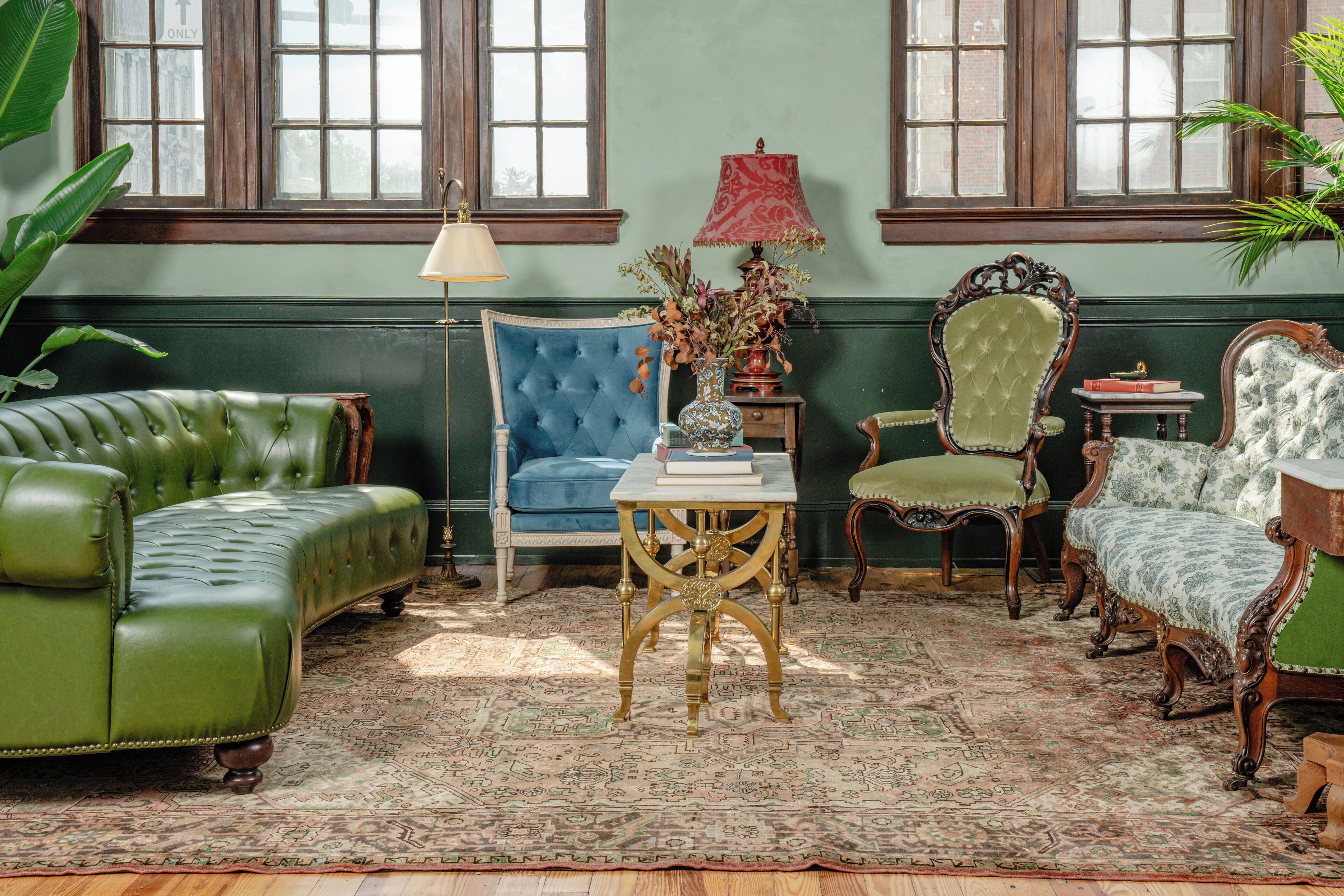 A room with a green sofa, a blue armchair, and a patterned rug.