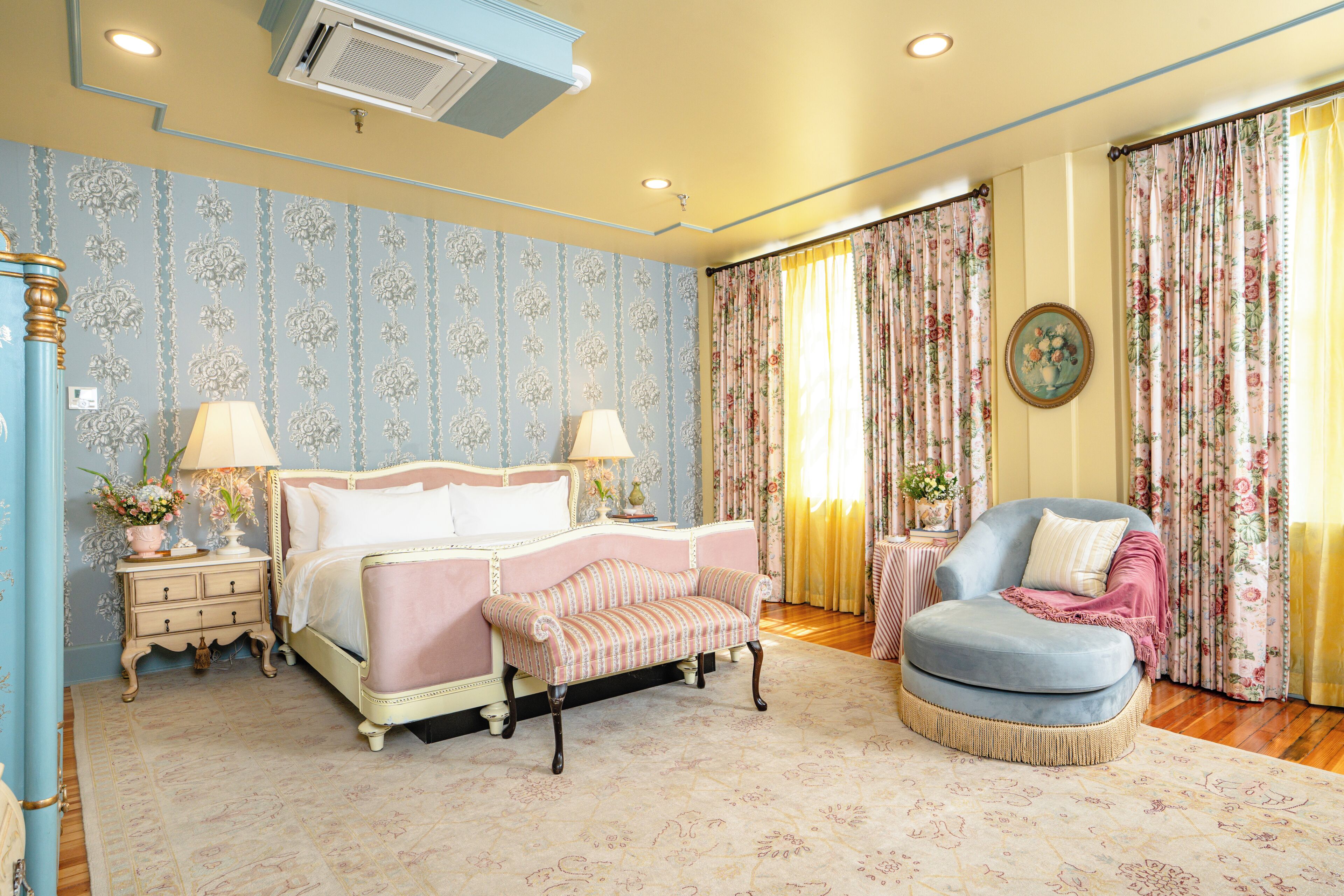 A bedroom with a bed, a chair, a nightstand, and curtains.
