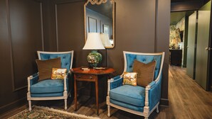 Two blue armchairs with brown cushions, a small wooden table with a lamp, and a mirror on the wall. - The Aldenberg Hotel (Versailles)