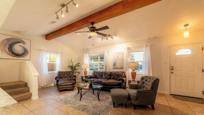Ein geräumiges Wohnzimmer mit Deckenventilator, Ledersofas, einem Couchtisch und einer Treppe zu einer weiteren Ebene.