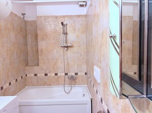 Une salle de bain équipée d’une baignoire, d’un pommeau de douche et d’une paroi de douche en verre.