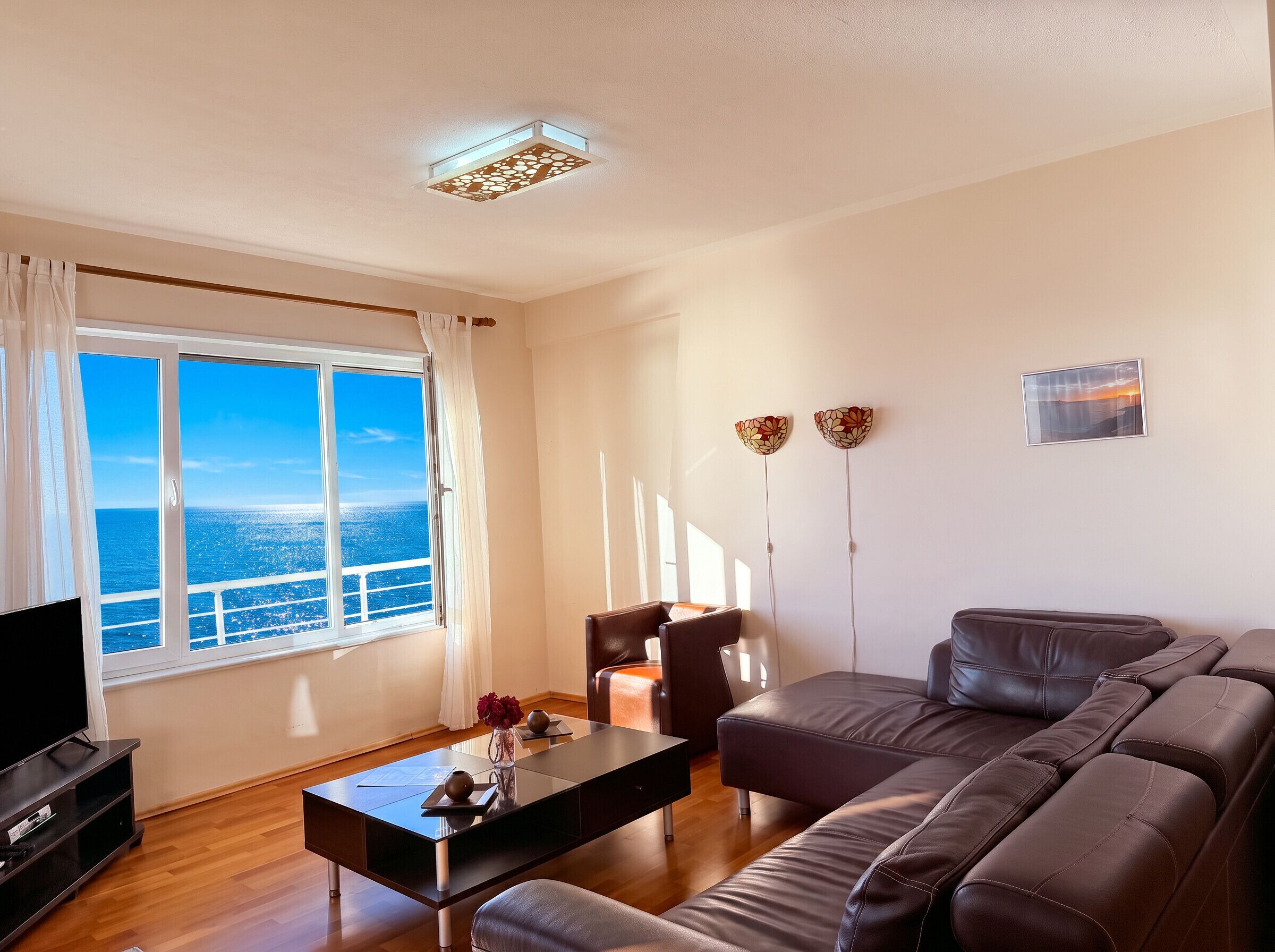 A living room with a large window, a sofa, a coffee table, and a television.