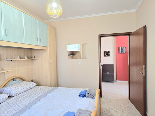 Une chambre à coucher comprenant un lit, une armoire, un miroir et une porte donnant accès à une salle de bain.