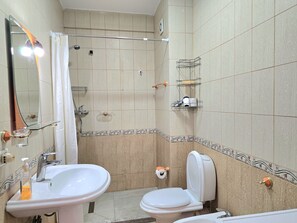 Un baño con lavamanos, inodoro, ducha y espejo.