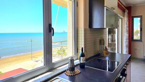 A kitchen with a view of the beach, a bottle of wine, and a coffee maker. - Dream View Apartment Durres 119 (Durres)