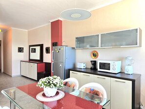 Cocina compacta con refrigerador, microondas, tostadora, cafetera y licuadora sobre la encimera.