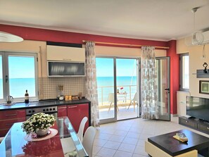 A modern kitchen with a large window, a dining area, and a TV.