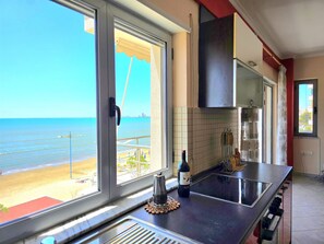 Une cuisine avec vue sur la plage, une bouteille de vin et une machine à café.
