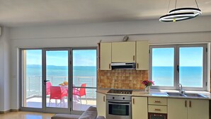 Une cuisine moderne avec vue sur la mer, un coin repas avec des chaises rouges et un canapé.