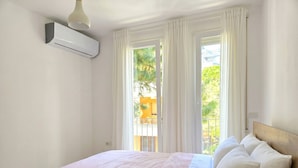 Une chambre à coucher avec un lit, des rideaux blancs et un appareil de climatisation.