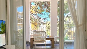 Un balcon avec une chaise, une table et un téléviseur posé sur un meuble.