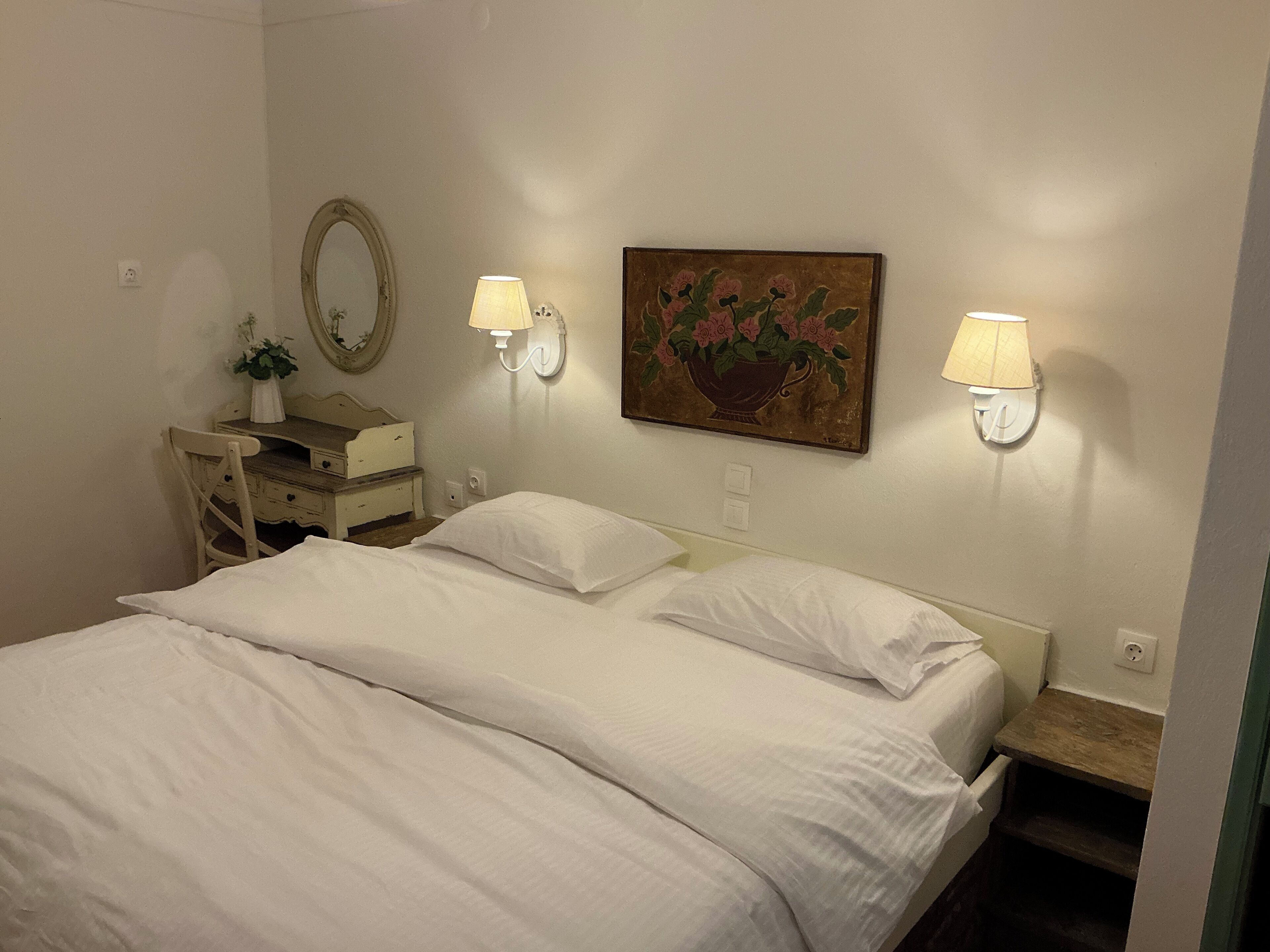 Ein Schlafzimmer mit zwei Betten, einem Schminktisch, einem Spiegel und Wandleuchten.
