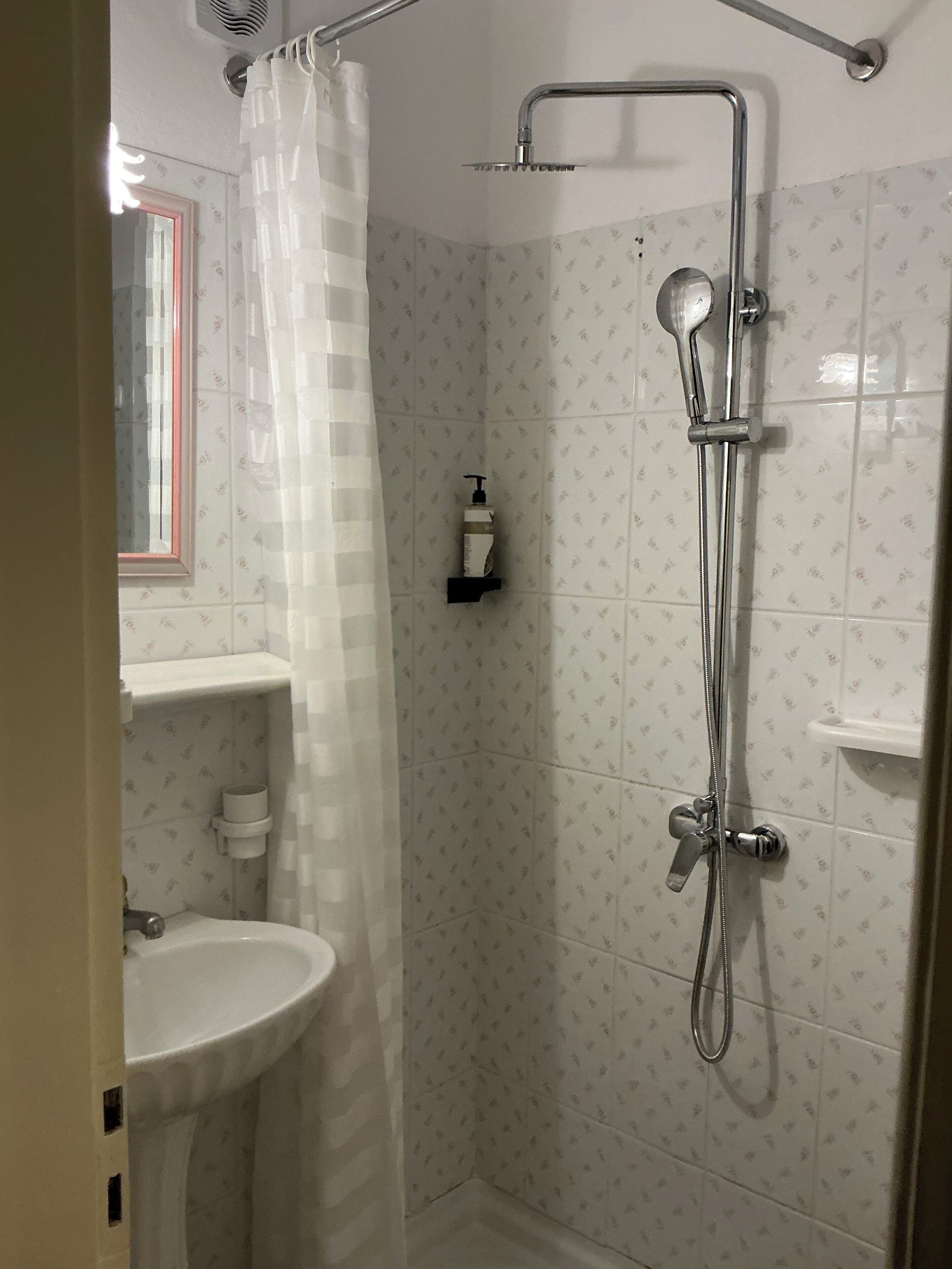 A shower with a handheld showerhead, a handheld showerhead, and a handheld showerhead.