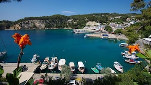 A coastal marina with boats docked, a clear blue sea, and a town in the background. - Liadromia Hotel (Alonissos)